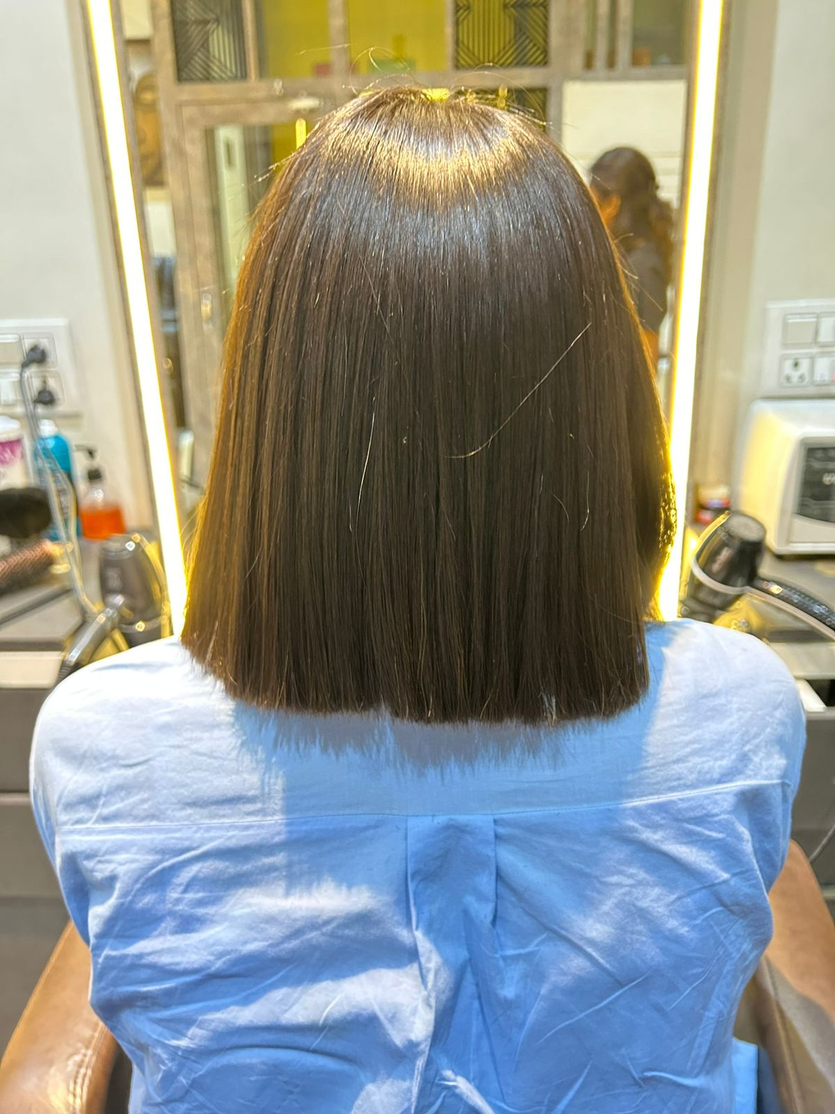Client after a blunt shoulder-length haircut with a sleek straight finish